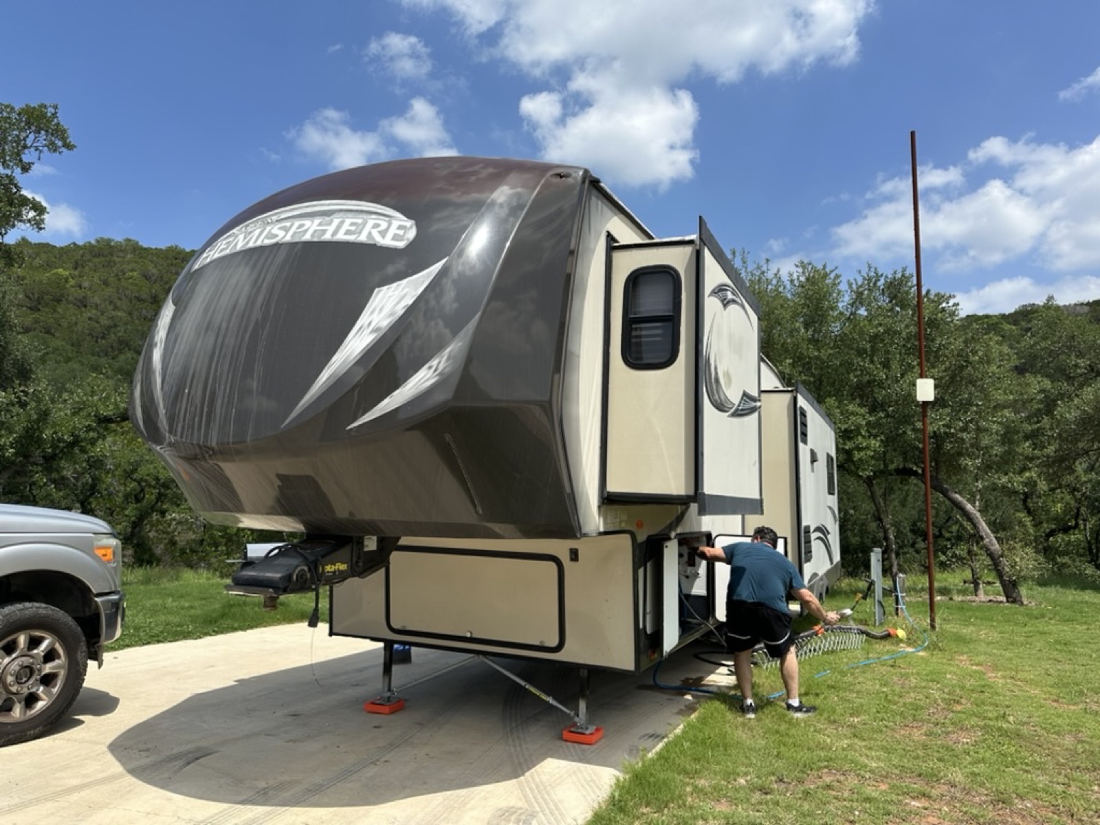 Front of the Hemisphere fifth wheel showing the elevated bedroom section and landing gear on orange leveling blocks